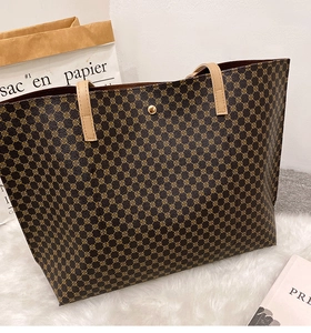 Macro detail of monogram print tote bag with brown leather handles and metallic buckle