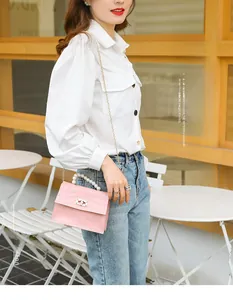 Detail der rosa Mini-Tasche mit Krokodilprägung, elegantem Perlengriff und goldener Kette