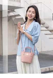 Detalle de bolso rosa con textura de cocodrilo, herrajes metálicos y correa al hombro