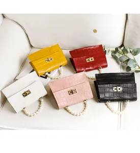 Nahaufnahme von fünf Mini-Taschen mit Krokodilmuster, Perlenhenkeln und Goldschlössern