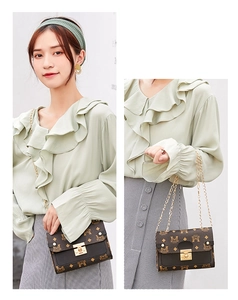 Detail of vintage crossbody bag with brown monogram print, black flap, and gold chain strap
