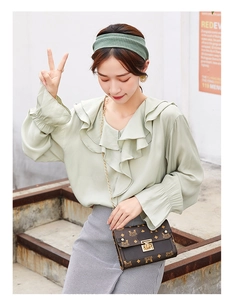 Close-up of light green blouse with ruffled collar and elasticated bell sleeves