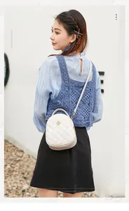 Close-up of white quilted mini backpack with metal flower logo on a casual outfit