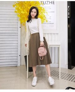 Close-up of a pink mini backpack paired with a pleated brown skirt and lace vest