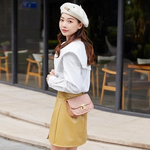 Pink quilted crossbody bag with gold chain strap and metal lock shown in a street scene