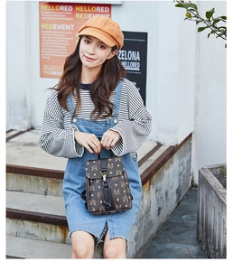 Detail of small dark brown faux leather backpack with classic monogram print and silver buckle