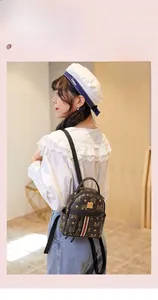 Close-up of brown PU leather mini backpack with monogram print and metal logo plate detail