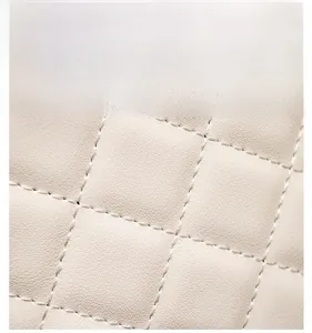 Detailed macro view of cream-colored quilted lychee pattern faux leather on a women bag