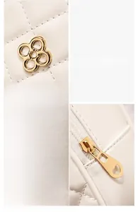 Detail of white quilted crossbody bag with golden flower hardware and smooth zipper