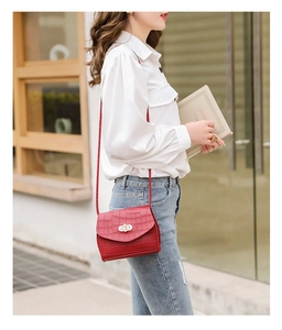 Detailed view of red crocodile embossed crossbody bag with luxury gold interlocking buckle