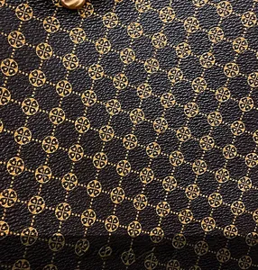 Macro shot of retro leather tote bag featuring golden clover print and lychee texture