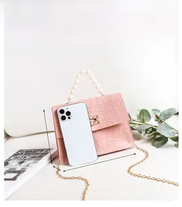 Detail der rosa Mini-Tasche mit Krokodilprägung, Perlengriff und goldener Kette