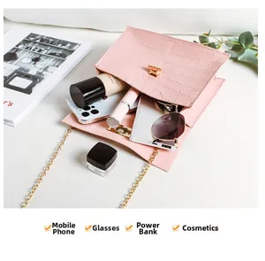 Detailansicht des geräumigen Innenraums einer rosa Mini-Tasche mit Krokodilmuster und Inhalt
