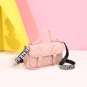 Sac bandoulière rose matelassé avec broderies losanges et sangle lettrée en décor de studio