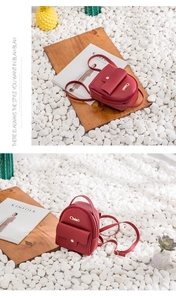 Macro shot of red faux leather mini backpack with gold magnetic buckle and metal logo