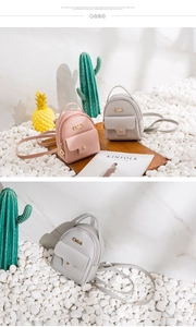 Detail of mini leather backpacks in pink and grey with metal logo and front pocket