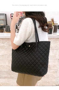 Close-up of black quilted tote bag with diamond pattern and gold metallic buckle