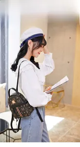 Close-up of mini backpack featuring retro monogram print and tricolor stripe detail