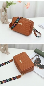 Close-up of caramel quilted crossbody camera bag with rainbow LOVE wide strap