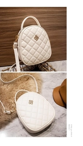 Close-up of white quilted handbag with golden clover hardware and chain strap details