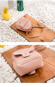 Detail of pink mini PU leather backpack with gold metal buckle on a rustic wood stand