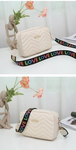 Detail of cream chevron quilted camera bag with stylish LOVE letter woven strap
