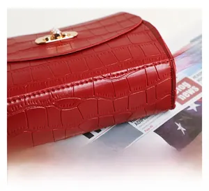 Detail of red crocodile texture bag showing double stitching and gold metal lock hardware