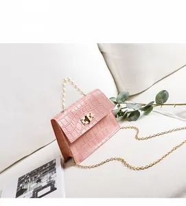 Detail der rosa Mini-Tasche mit Krokodilprägung, Perlengriff und goldener Kette