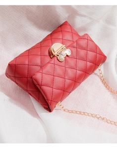 Detail of red quilted shoulder bag with gold cartoon-shaped lock and metal chain