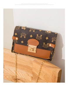 Detail of vintage square crossbody bag with chain strap and gold clasp on wooden bench