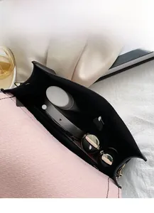Internal view of a small square crossbody bag showing storage for makeup and lipstick