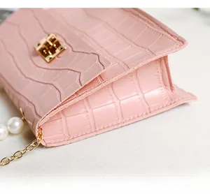 Detail der rosa Mini-Tasche mit Krokodilprägung, Perlenkette und goldenem Drehverschluss