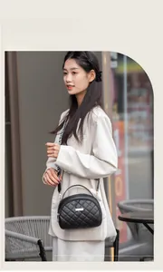 Détail du sac bandoulière noir matelassé avec sangle à lettres porté par un mannequin
