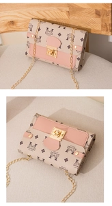 Detail of a beige crossbody bag with pink leather trim and elegant gold chain strap