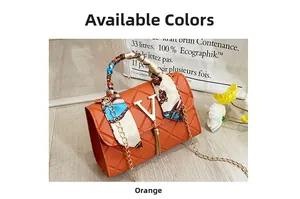 Detail of orange red crossbody bag with quilted pattern, silk scarf, and gold V logo tassel