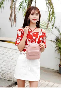Close-up of pink PU leather mini backpack with zippered front pocket shown on a model