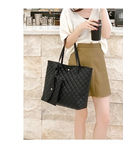 Detail of black quilted tote bag with matching mini pouch on a female shoulder