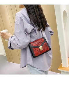 Detail of red snake pattern shoulder bag with gold chain strap and metal lock closure