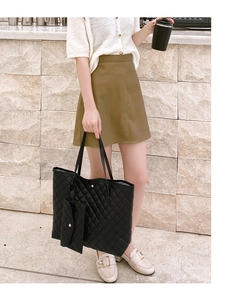 Detail of black quilted tote bag featuring a diamond pattern and small matching pouch