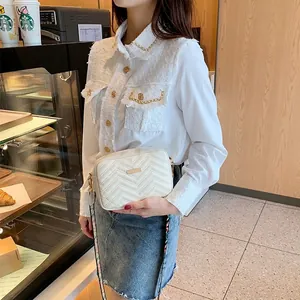 Sac bandoulière blanc à matelassage en V, détails dorés et sangle lettrée sur modèle