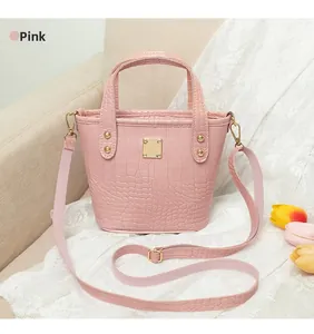 Detalle de bolso bucket rosa con grabado de cocodrilo y herrajes dorados sobre encaje
