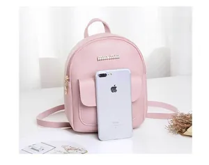 Close-up of pink mini backpack with gold zippers and brand logo on a white desk