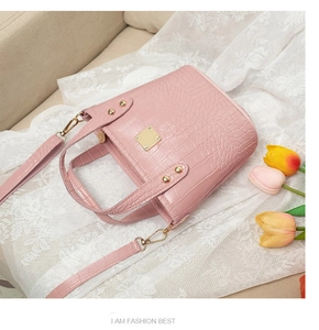 Detalle de bolso bucket rosa con textura de cocodrilo y hebilla cuadrada dorada