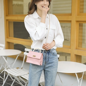 Rosa Mini-Tasche mit Krokodilprägung, Perlengriff und Goldkette getragen von einem Model
