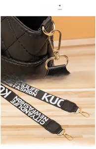 Detail of black quilted bucket bag featuring gold hardware and embroidered woven strap