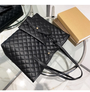 Close-up of black quilted tote bag with matching pouch on a glass coffee table