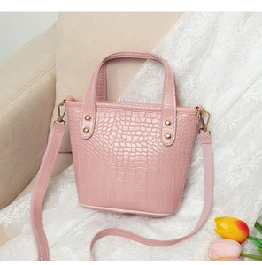 Bolso cubo rosa con grabado de cocodrilo y remaches dorados sobre encaje blanco