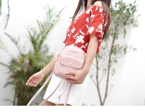Detail of light pink mini PU leather backpack with magnetic flap pocket and metal hardware