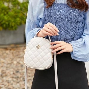 Quilted cream crossbody bag with double zippers and gold floral emblem for women