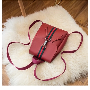 Detail of red faux leather backpack featuring striped ribbon and silver hook closure